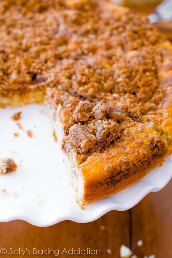 super crumb coffee cake on a white cake stand with a slice removed
