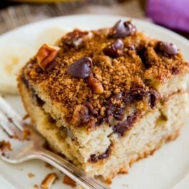 slice of banana chocolate chip crumb cake on a white plate with a fork