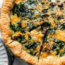 slice of spinach quiche cut out before removing from pie dish.