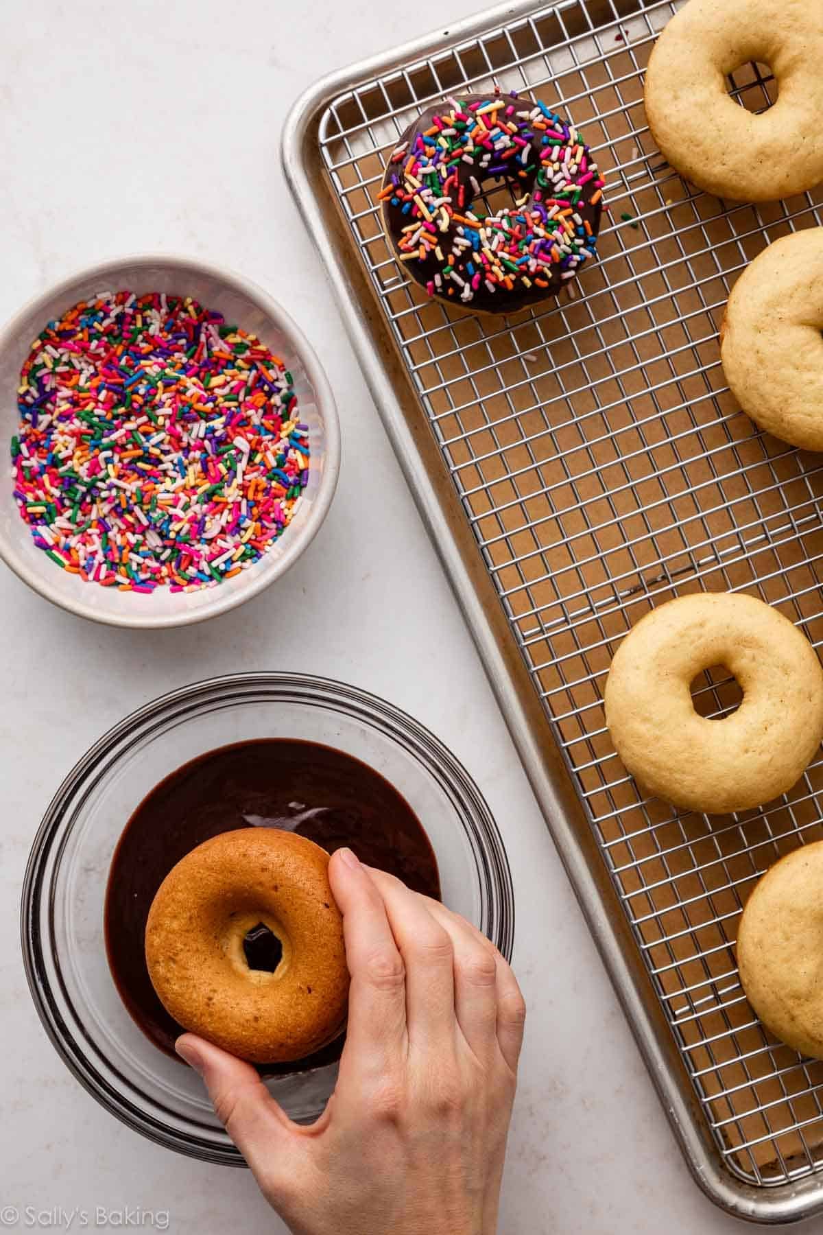 hand dipping donut in icing.