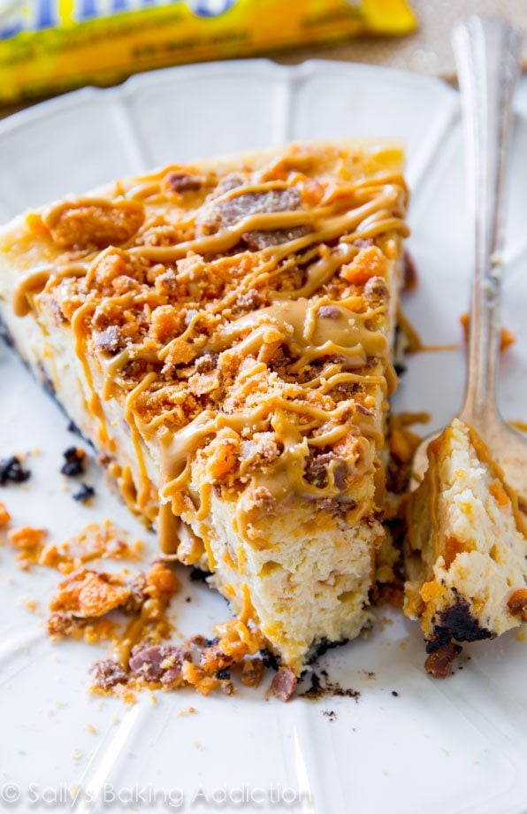 slice of peanut butter Butterfinger cheesecake on a white plate with a fork