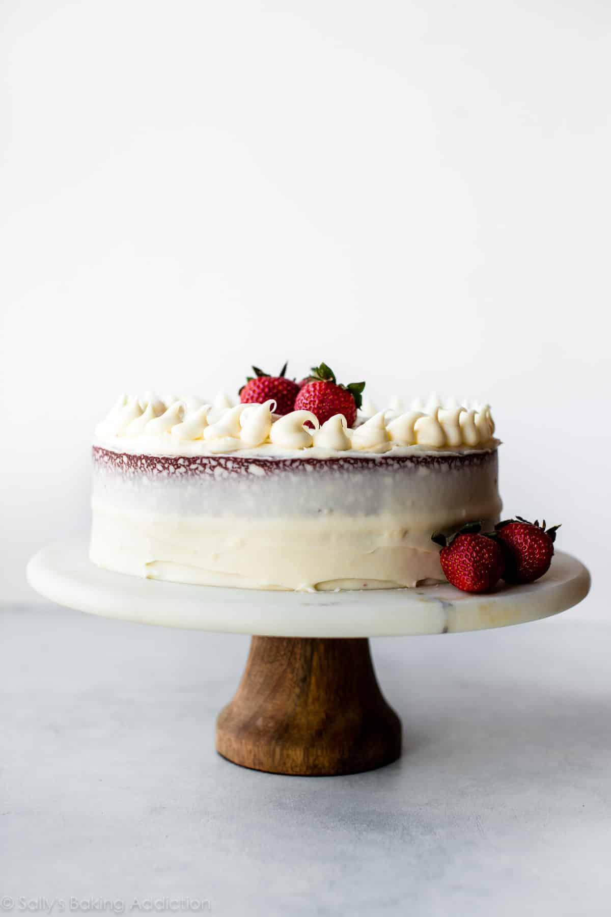 red velvet layer cake on a marble and wood cake stand