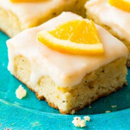 glazed orange poppy seed bars on a blue plate