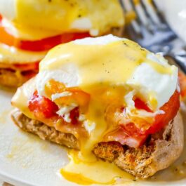 eggs benedict on a white plate with a fork