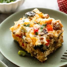 slice of egg and sausage breakfast casserole on green plate.