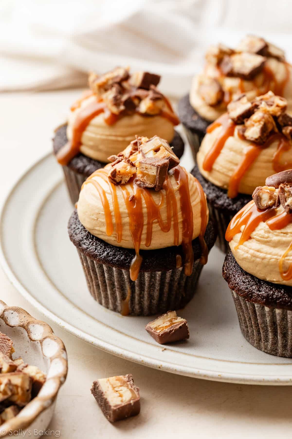 snickers cupcakes with peanut butter frosting and caramel drizzle.