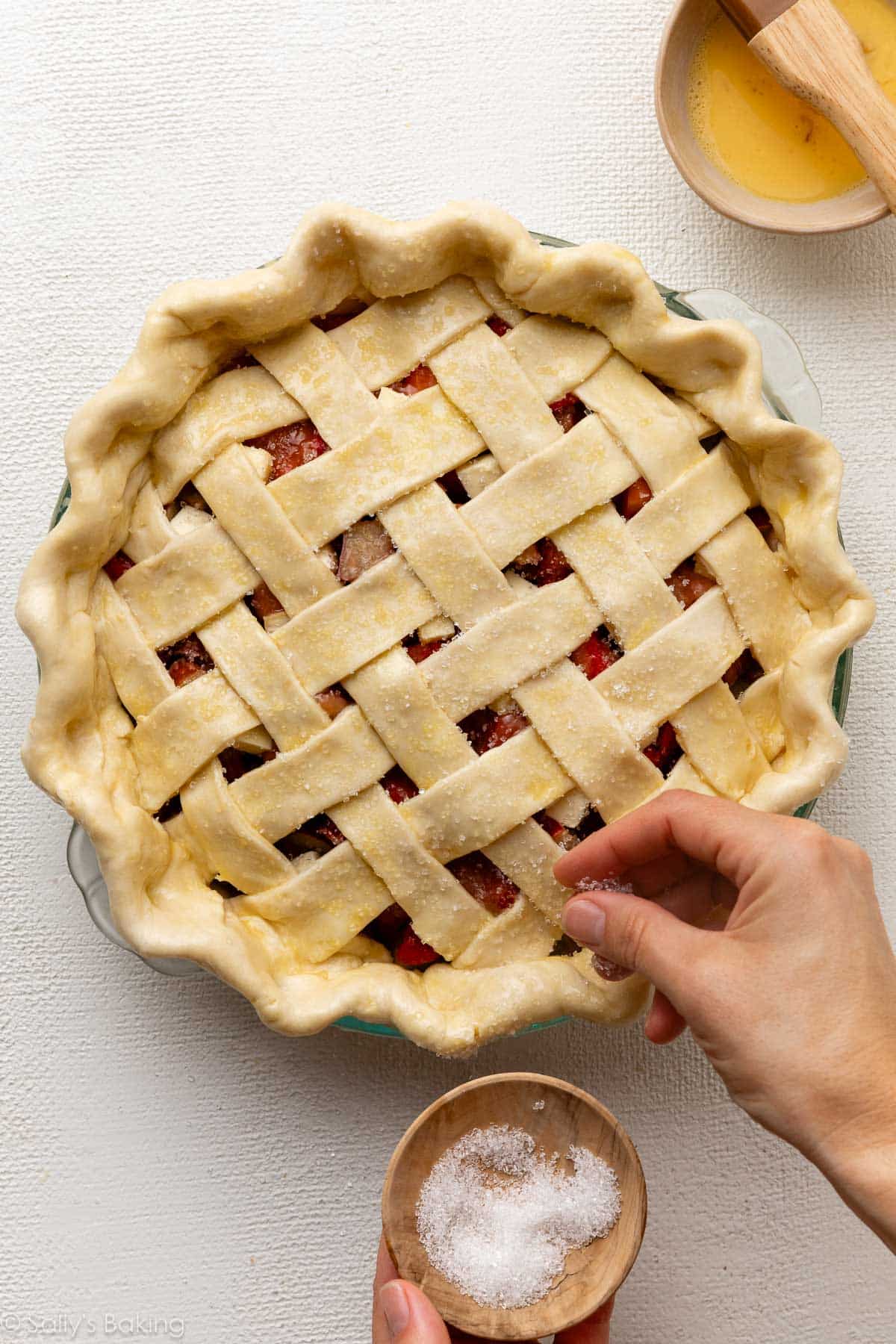 hand sprinkling coarse sugar on top of pie.
