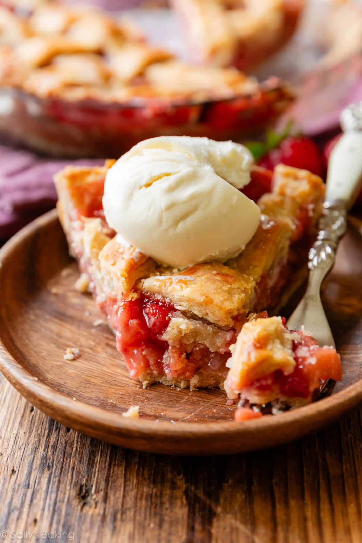 slice of strawberry rhubarb pie with ice cream on top.