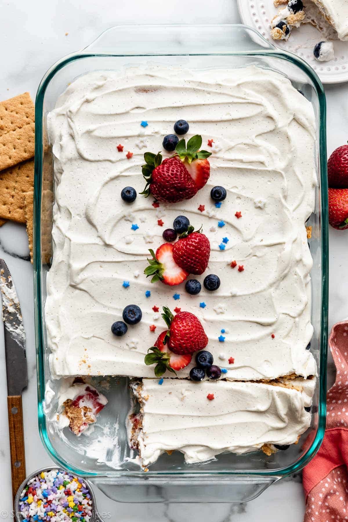 overhead photo of berry icebox cake with fresh strawberries, blueberries, and star sprinkles on top.