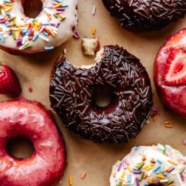 doughnut frostings on doughnuts including chocolate, strawberry, and vanilla-topped doughnuts.