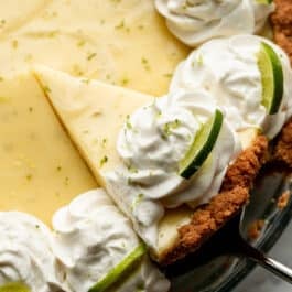 slice of key lime pie being removed from glass pie dish.