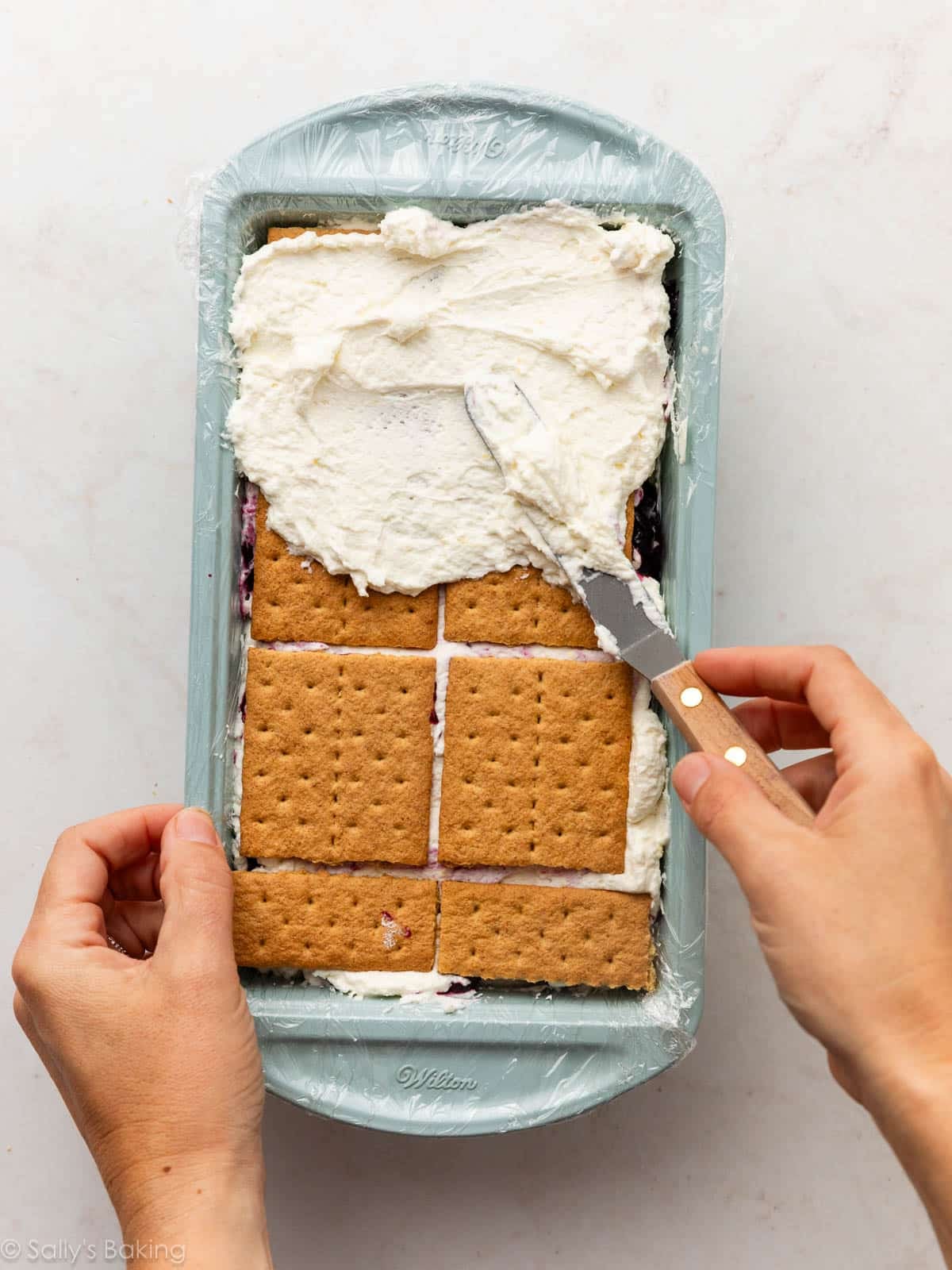spreading cream on graham crackers in loaf pan.
