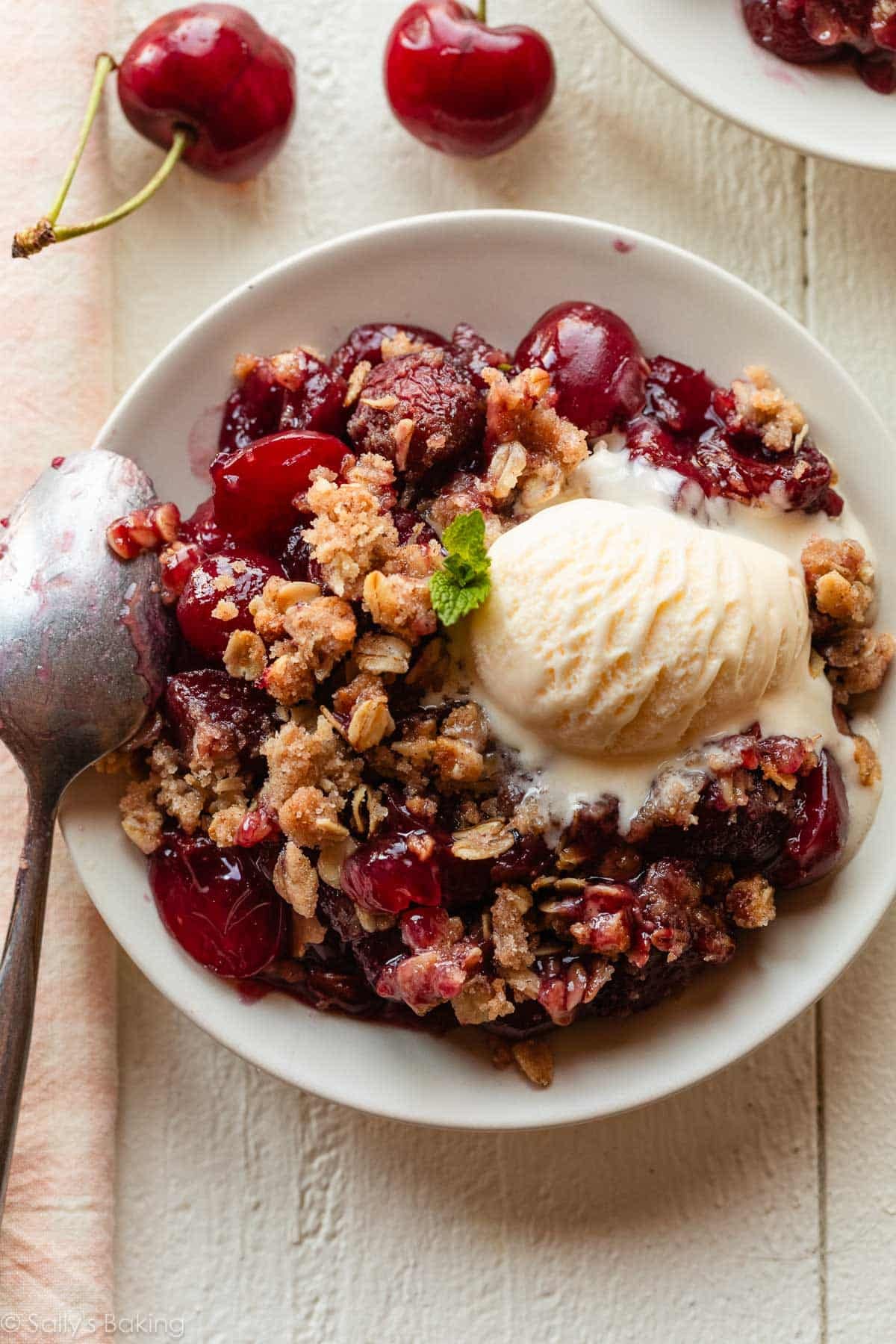 serving of cherry crisp on plate with vanilla ice cream.