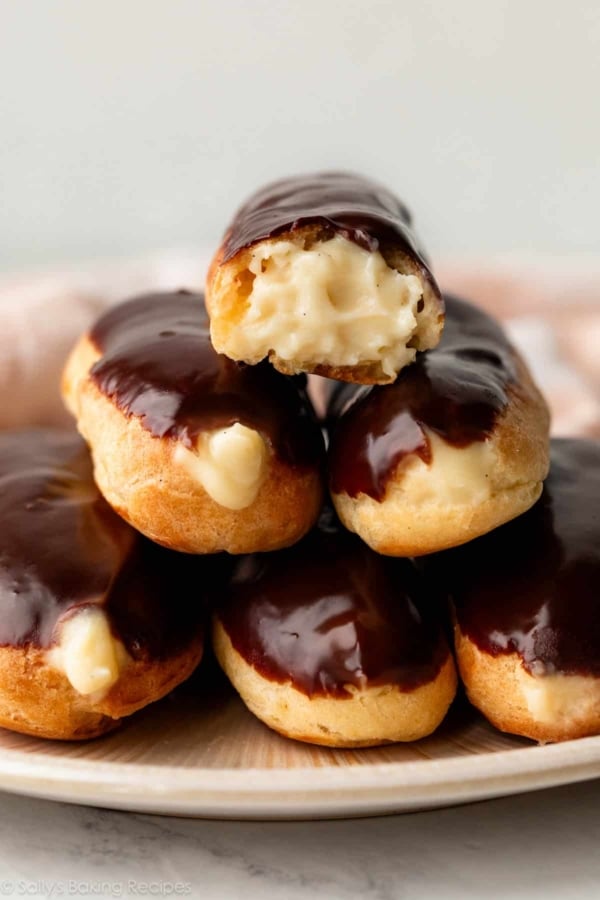 homemade eclairs with pastry cream piled on plate.