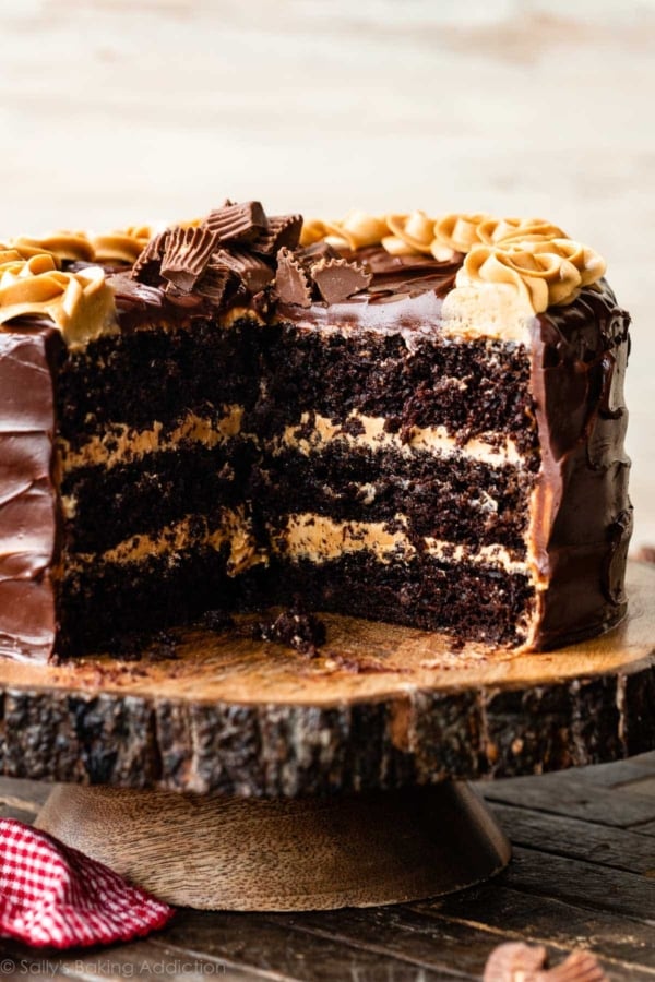 3 layer chocolate cake with peanut butter frosting and dark chocolate ganache on wood cake stand.