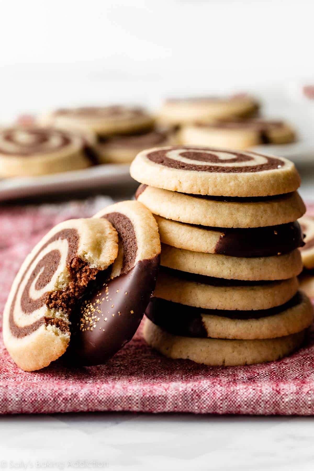 stack of chocolate and vanilla pinwheel cookies on red linen.