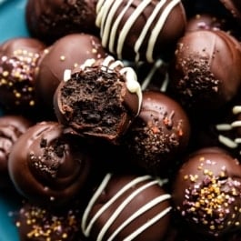 oreo balls on blue plate with some drizzled with white chocolate and others with gold sprinkles.