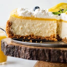 removing a slice of lemon cheesecake with lemon curd and whipped cream from base of springform pan.