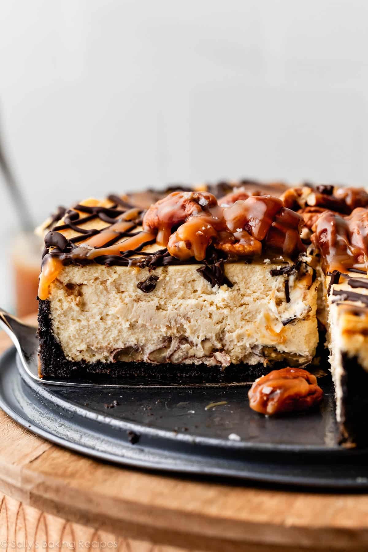 slice of caramel turtle cheesecake being removed from springform pan.