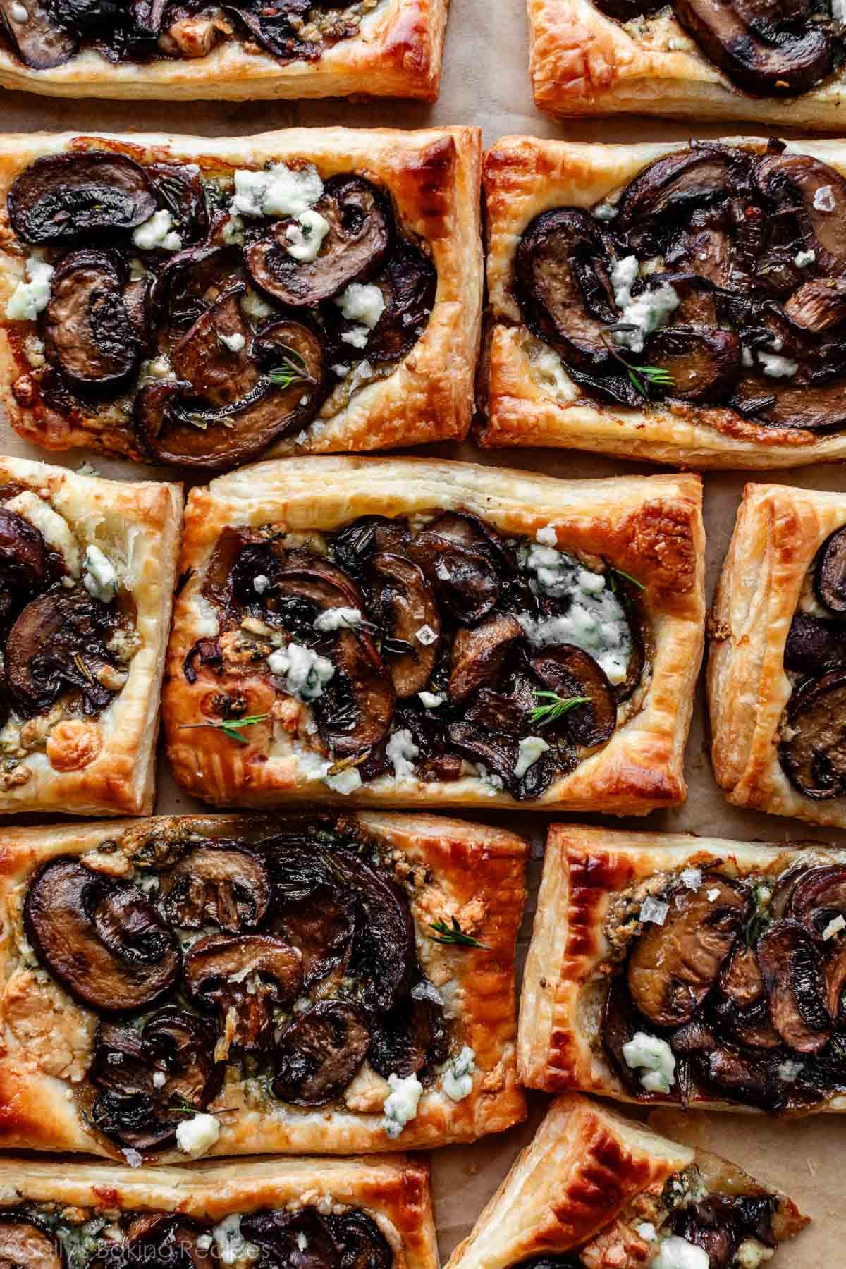 individual mushroom puff pastry tarts lined together on parchment paper.