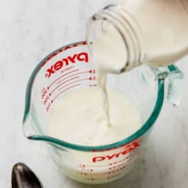 pouring milk into liquid measuring cup with lemon juice.