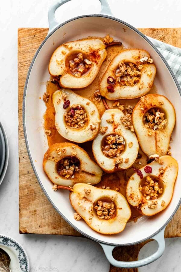 baked pears in blue and white oval baking pan on wooden cutting board.