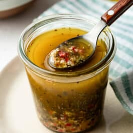 jar of homemade Italian dressing with a spoon.