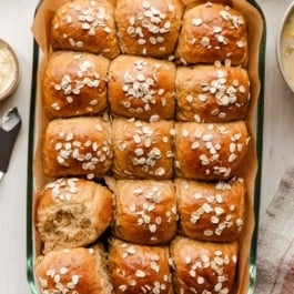 oatmeal molasses dinner rolls with oats on top.