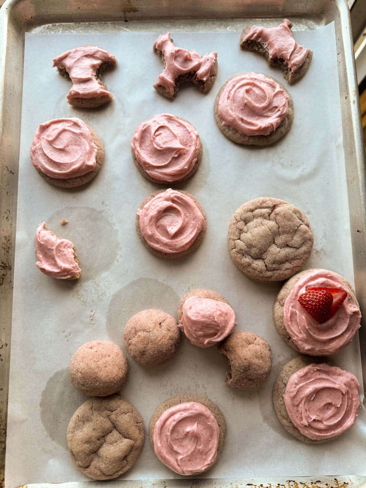 strawberry cookies with frosting on baking sheet.
