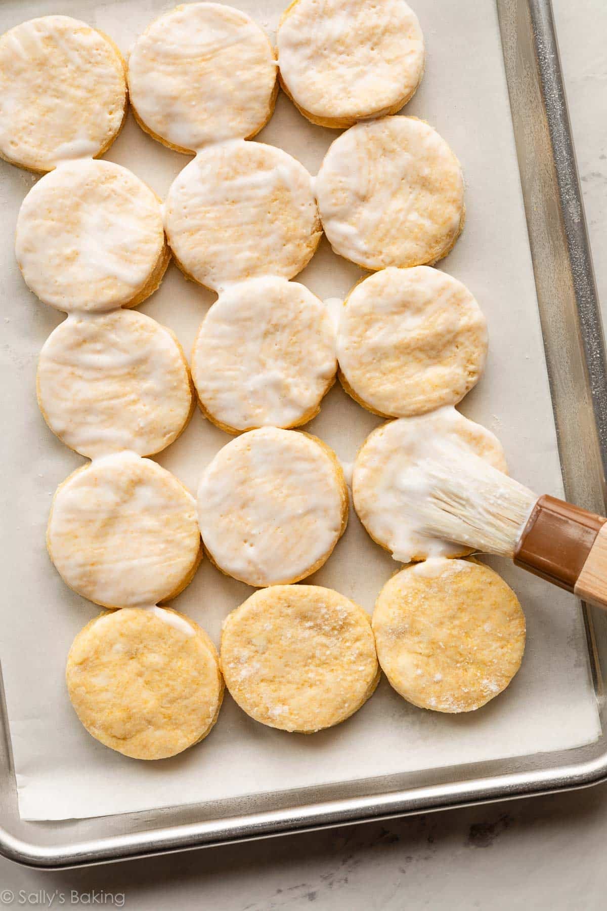 cornmeal biscuits being brushed with buttermilk.