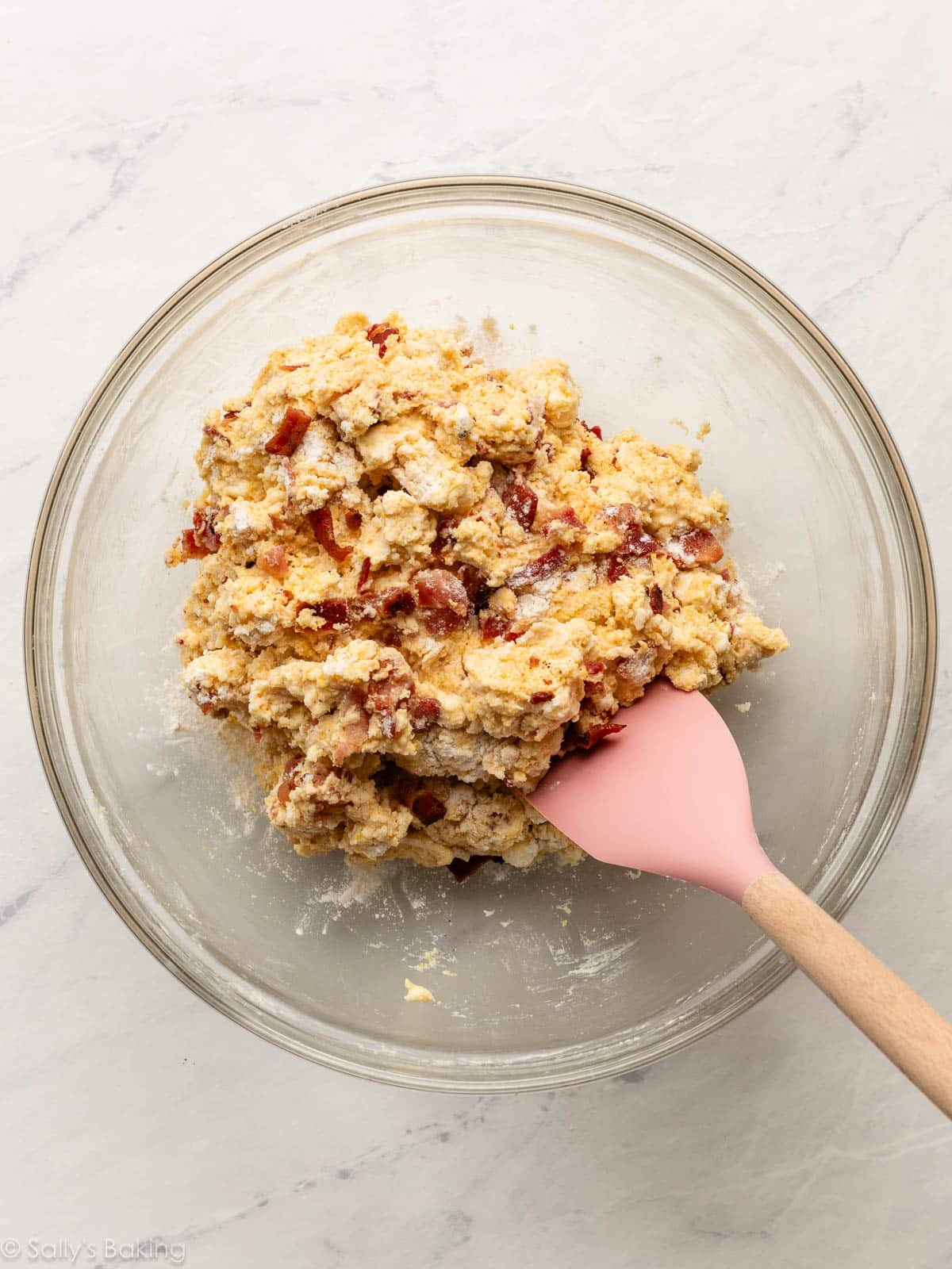 bacon dough in glass bowl with pink spatula.