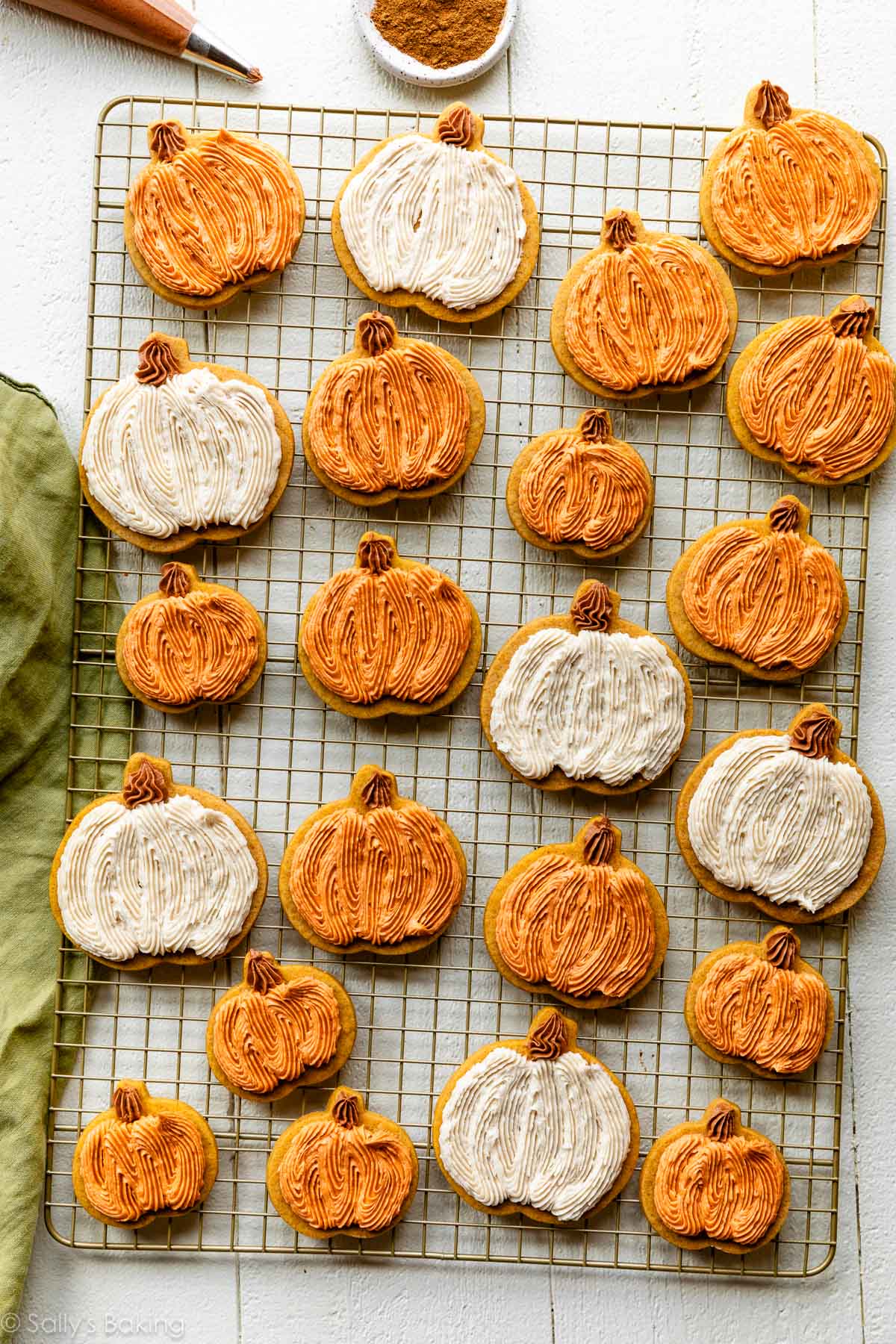 Frosted pumpkin sugar cookies arranged on a cooling rack.