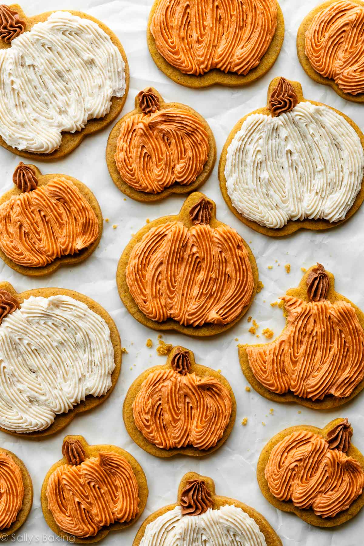 Frosted pumpkin sugar cookies on parchment paper.